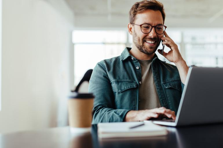 Hombre sonriendo mientras trabaja frente a un computador